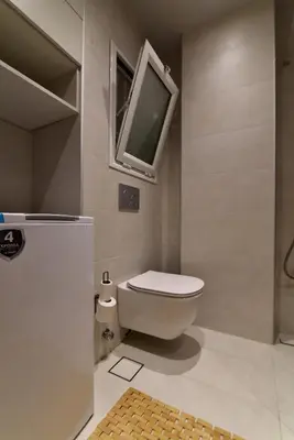 a bathroom with a toilet and a tv on the wall at Fos Apartment - Ippokratous 2BDR Central Flat in Athens