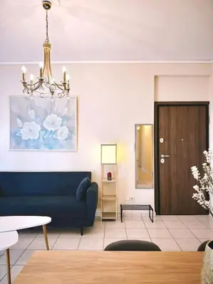 a living room with a blue couch and a chandelier at Cozy apartment in Voula in Athens