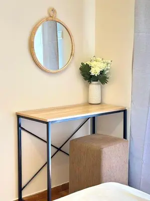 a table with a mirror and a vase with flowers on it at Cozy apartment in Voula in Athens