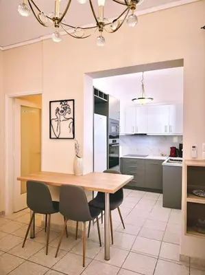 a kitchen with a wooden table and chairs at Cozy apartment in Voula in Athens