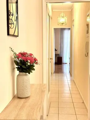 a hallway with a vase of flowers on a table at Cozy apartment in Voula in Athens