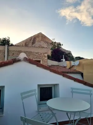 a table and chairs on a balcony with a mountain at Lemon Tree House with garden in Plaka in Athens