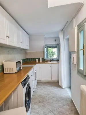 a kitchen with white cabinets and a washer and dryer at Lemon Tree House with garden in Plaka in Athens