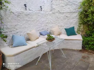 a couch with pillows and a table in front of a wall at Lemon Tree House with garden in Plaka in Athens