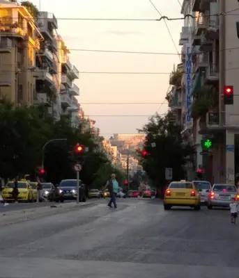 a man crossing a street in a city with traffic at Edem apartments in Athens