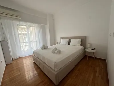 a white bedroom with a large bed and a window at Zografou centre apartment in Athens