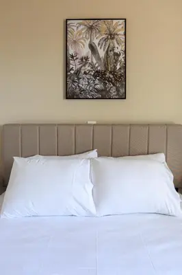 a bed with white sheets and a picture on the wall at AIOLOS elegant escapes GLYFADA apartment in Athens