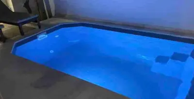a blue swimming pool in a room with a chair at Luxury 6 bedroom 4 bathroom villa with pool in Vari