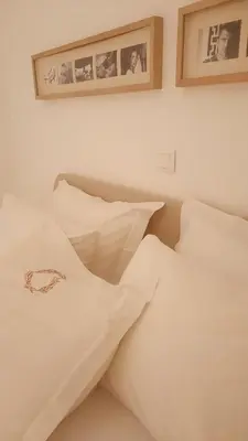 a bed with white sheets and pictures on the wall at Penelope's in Athens