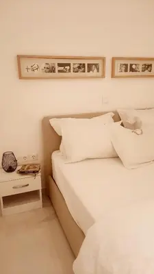 a bedroom with a bed with white sheets and a table at Penelope's in Athens