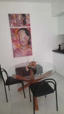 a glass table with two chairs and a painting on the wall at Penelope's in Athens