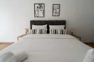 a bedroom with a large white bed with three pictures on the wall at 2BR Apartment next to the Metro station in Athens