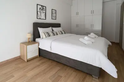 a bedroom with a large white bed and a wooden floor at 2BR Apartment next to the Metro station in Athens