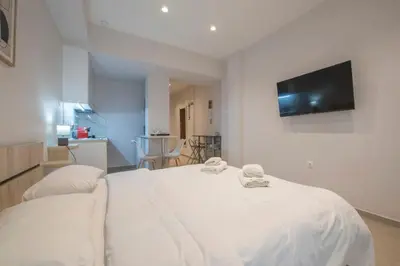 a bedroom with a white bed with a flat screen tv on the wall at Koukaki Sofia's Apartment in Athens