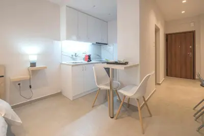 a kitchen with white cabinets and a table and chairs at Koukaki Sofia's Apartment in Athens