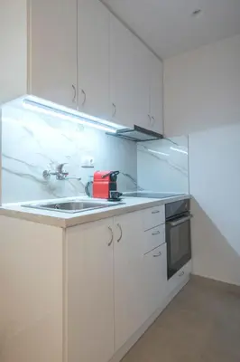 a white kitchen with a sink and a red appliance at Koukaki Sofia's Apartment in Athens