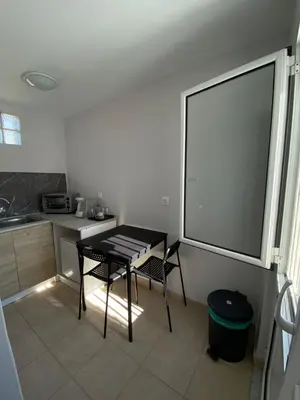 a kitchen with a table and two chairs and a window at Fanis Rooms in Aghia Marina