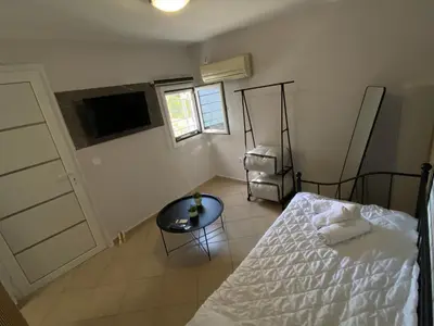 a bedroom with a bed and a table and a tv at Fanis Rooms in Aghia Marina