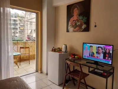 a living room with a desk with a computer and a refrigerator at LEONEG corner in Athens