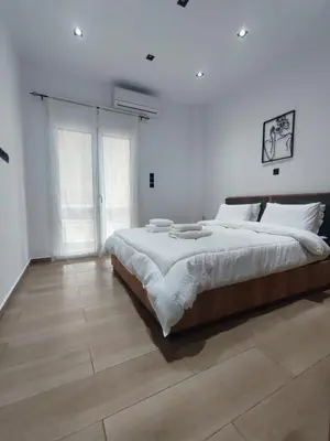 a white bedroom with a large bed and a wooden floor at Harmony Twin Lofts Metaxourgeio 1 in Athens