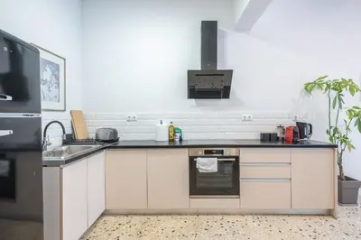 a kitchen with white cabinets and a black counter top at Zen Spacious, Psirri in Athens