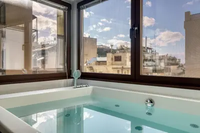 a bath tub with a view of a city from a window at GSM Elevated Luxury Suites in Athens