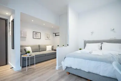 a white bedroom with a bed and a couch at Stylish apartment at Exarchia in Athens