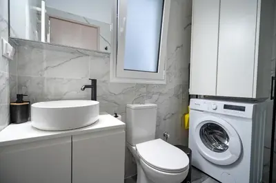 a bathroom with a toilet and a sink and a washing machine at Stylish apartment at Exarchia in Athens