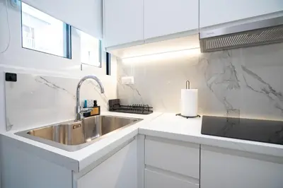 a white kitchen with a sink and a window at Stylish apartment at Exarchia in Athens