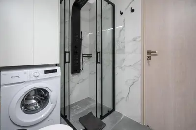 a bathroom with a washing machine and a glass shower at Stylish apartment at Exarchia in Athens