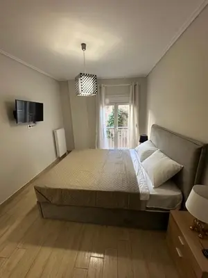a bedroom with a large bed and a window at Kosmos luxury apartment in Athens