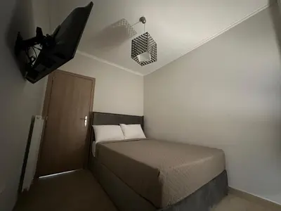 a small bedroom with a bed and a tv on the ceiling at Kosmos luxury apartment in Athens