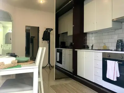 a kitchen with white cabinets and a table and a counter at Central flat in Pagrati in Athens