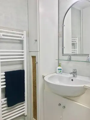a white bathroom with a sink and a mirror at Central flat in Pagrati in Athens