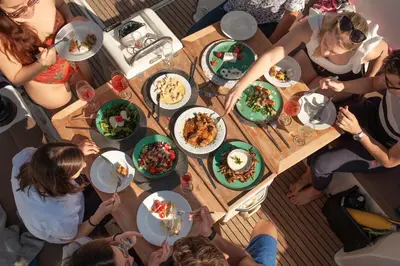 a group of people sitting around a table with food at Luxury Sailing Cruises in Athens with Traditional Greek Cuisine and Drinks in Athens