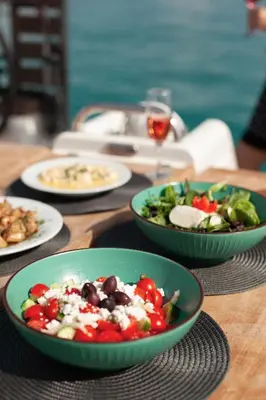 a table with plates of food and bowls of food at Luxury Sailing Cruises in Athens with Traditional Greek Cuisine and Drinks in Athens