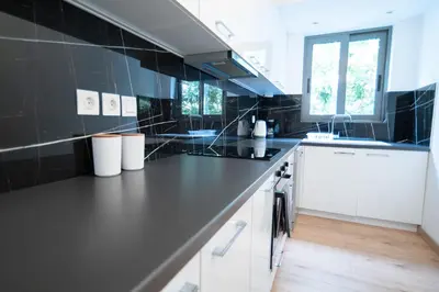 a kitchen with black tiled walls and white cabinets at Elegant apartment in Agia Paraskevi-B2 in Athens