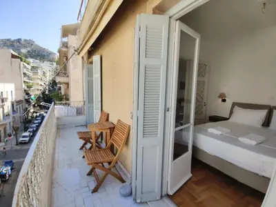 a balcony with a bedroom and a bed and chairs at Stylish 1BR Apt with Retro Kitchen View Balcony in Athens