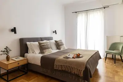 a bedroom with a large bed and a chair at Acropolis Museum Retreat - 2 Bedroom Apartment in Athens