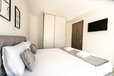 a bedroom with a white bed and a television at City-View Apartment by Piraeus Port - DRF2 in Piraeus