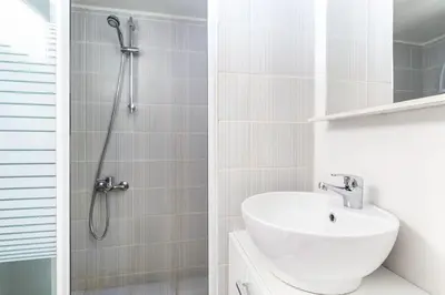 a white bathroom with a shower and a sink at Modern Apt opposite the Acropolis Museum in Athens