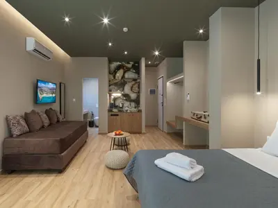 a bedroom with a bed and a couch and a kitchen at YaPe Coastal Suites at Alimos Beach in Athens
