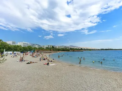 a group of people swimming in the water at a beach at YaPe Coastal Suites at Alimos Beach in Athens