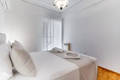 a white bedroom with a white bed with white pillows at Hephaestus - Luxury & Modern Apartment in Psychiko in Athens