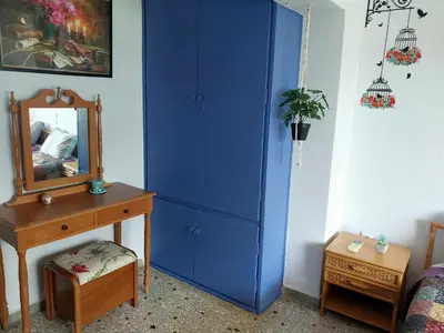 a blue cabinet in a bedroom with a mirror and a dresser at Studio By The Beach 2 in Saronida