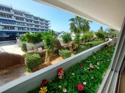 a balcony with a garden with flowers and palm trees at Studio By The Beach 2 in Saronida