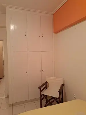 a bedroom with white cabinets and a white chair at Minimal Stoudio in Athens