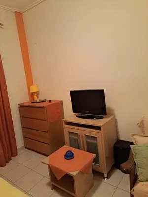 a living room with a tv on a dresser with a table at Minimal Stoudio in Athens