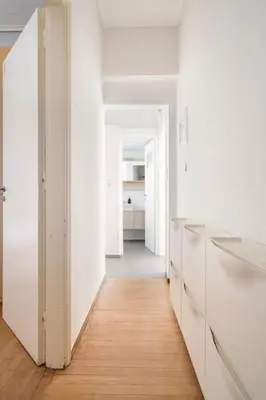 a kitchen with white cabinets and a wooden floor at Sunny southern Athens flat near the seaside in Athens