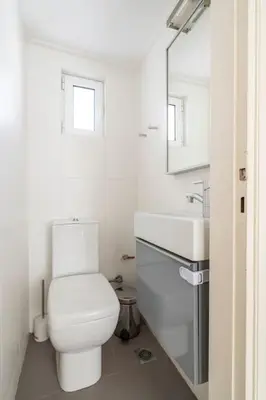 a white bathroom with a toilet and a sink at Sunny southern Athens flat near the seaside in Athens
